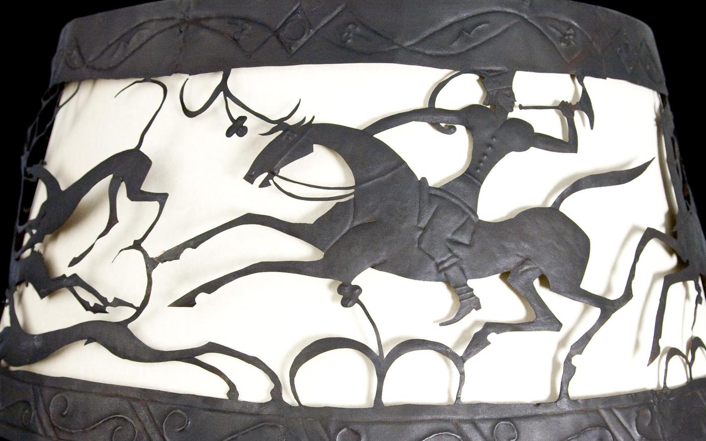 Metal cutout lamp shade depicting a man on a horse...